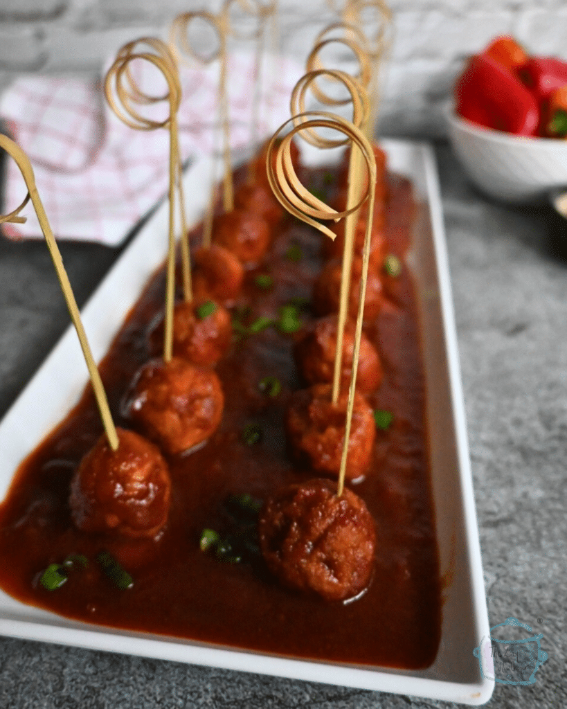 Guinness glazed meatballs on a tray with decorative picks for appetizers