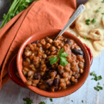 madras lentils in a clay bowl with a spoon and some naan on the side