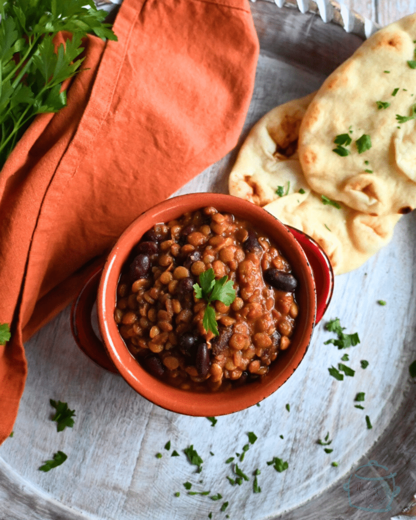 madras lentils in a clay bowl with some naan on the side  