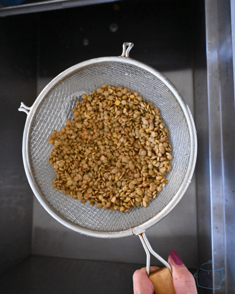 lentils in a colander over a sink after being rinsed