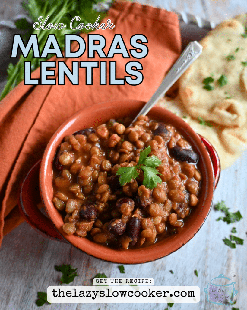 madras lentils in a clay bowl with a spoon and some naan on the side