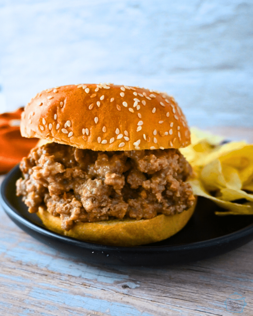 chicken satay sloppy joe on a sesame seed bun with potato chips in the background