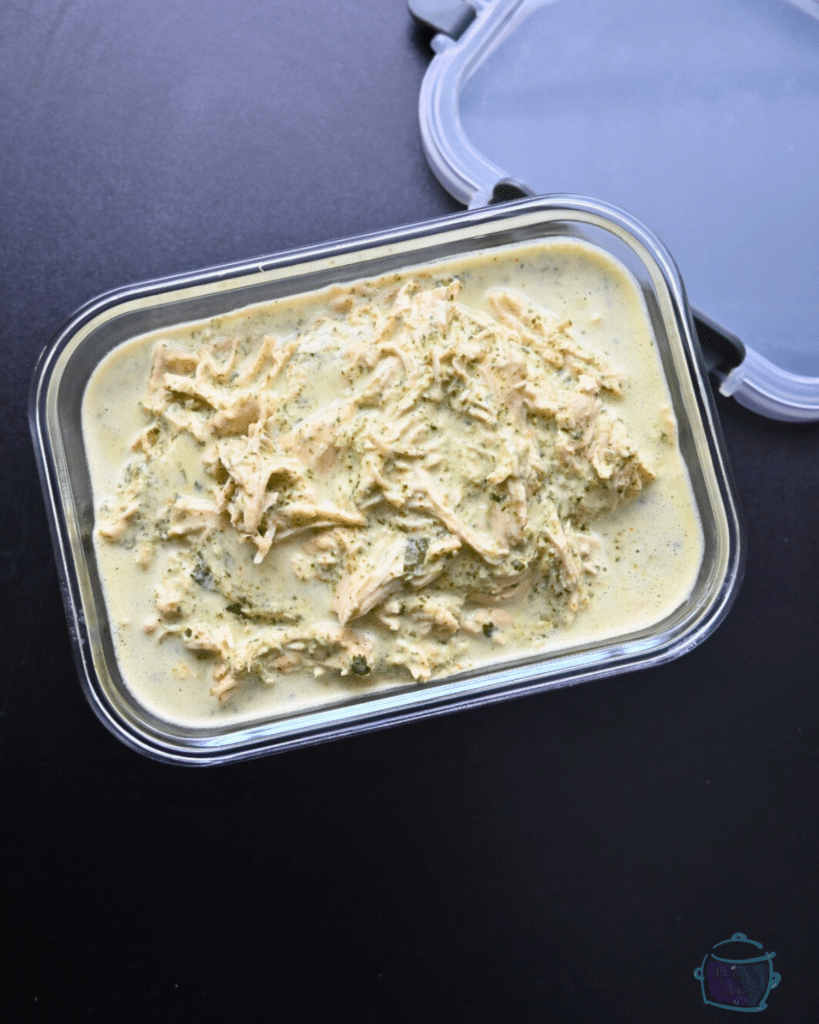 a container of creamy shredded slow cooker chicken ready to be stored in the freezer or fridge.