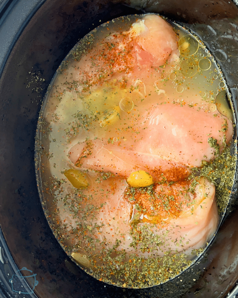 chicken breasts, seasonings and broth in a slow cooker prior to cooking