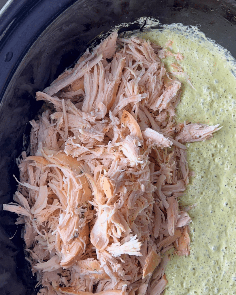 shredded chicken on top of creamy cilantro lime sauce in a slow cooker