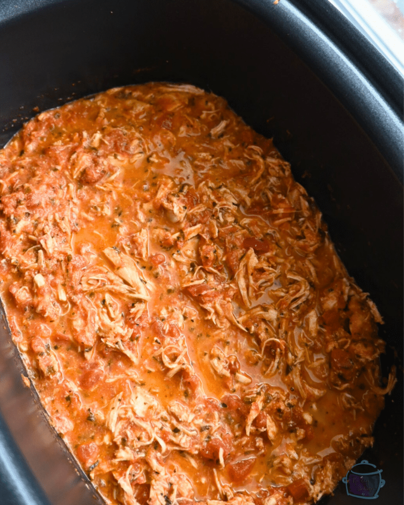 tomato basil chicken in a crockpot after cooking and shredding the chicken