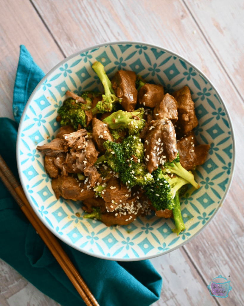 Orange beef and broccoli in a blue and white bowl.