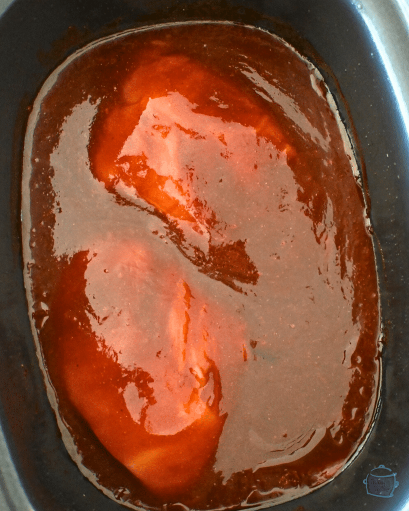 raw turkey tenderloins in a slow cooker full of homemade bbq sauce ingredients