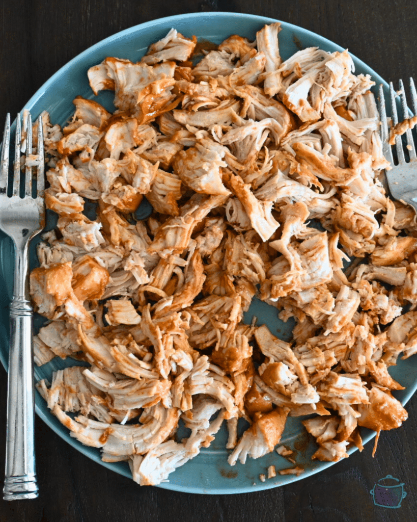 shredded bbq turkey tenderloin on a plate with shredding forks