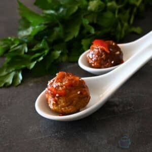 two meatballs on white ceramic soup spoons