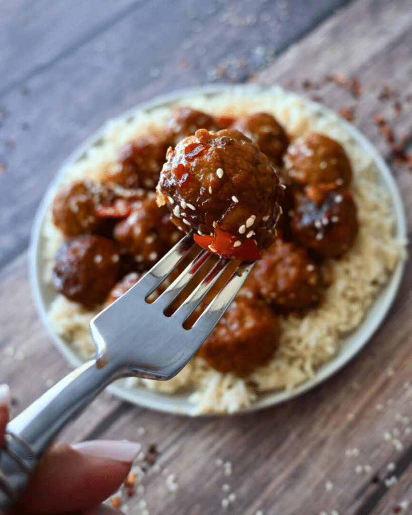 sweet chili meatballs on a fork over a plateful of the same