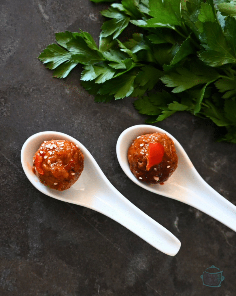 two meatballs on white ceramic soup spoons