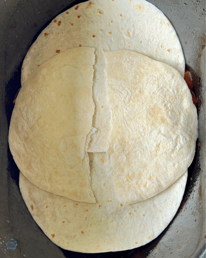 a layer of tortillas in a crockpot