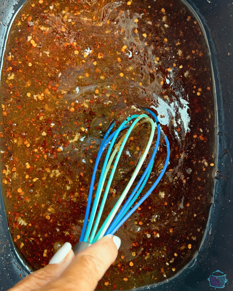 hot honey sauce being whisked together in a slow cooker