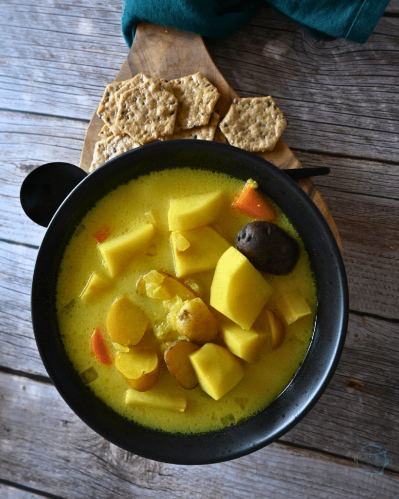 a bowl of ginger turmeric root vegetable soup with some crackers