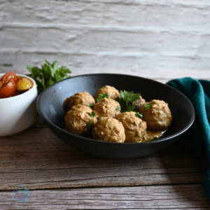 a black bowl with lemon tahini meatballs in the center