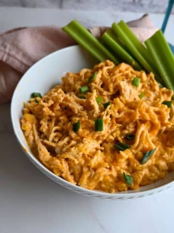 chicken buffalo ramen in a bowl ready to serve with celery stalks on the side