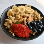 a bowl of breakfast quinoa cooked in a slow cooker topped with sliced bananas and strawberries