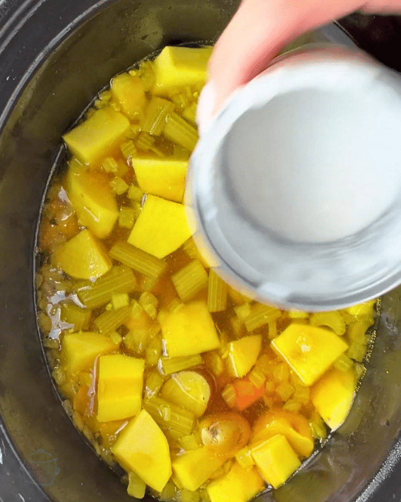 adding coconut milk to a slow cooker cooker full of ginger turmeric root veggie soup