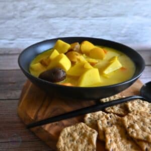 a bowl of ginger turmeric root vegetable soup with some crackers