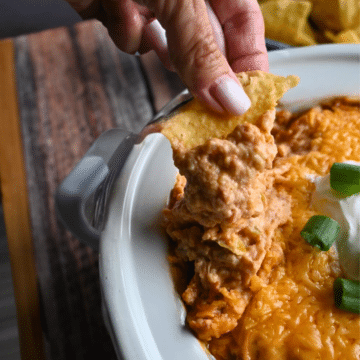 Texas trash dip being scooped up out of a slow cooker onto a tortilla chip