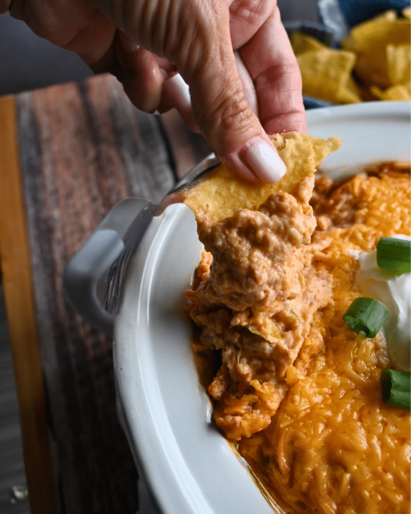 Texas trash dip being scooped up out of a slow cooker onto a tortilla chip