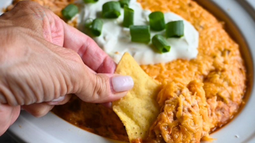 Texas trash dip being scooped up out of a slow cooker onto a tortilla chip