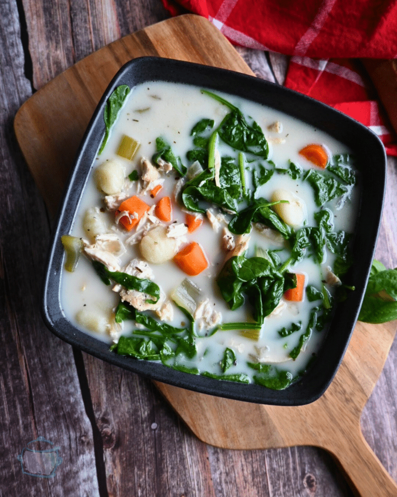 slow cooker chicken gnocchi soup in a square black bowl.