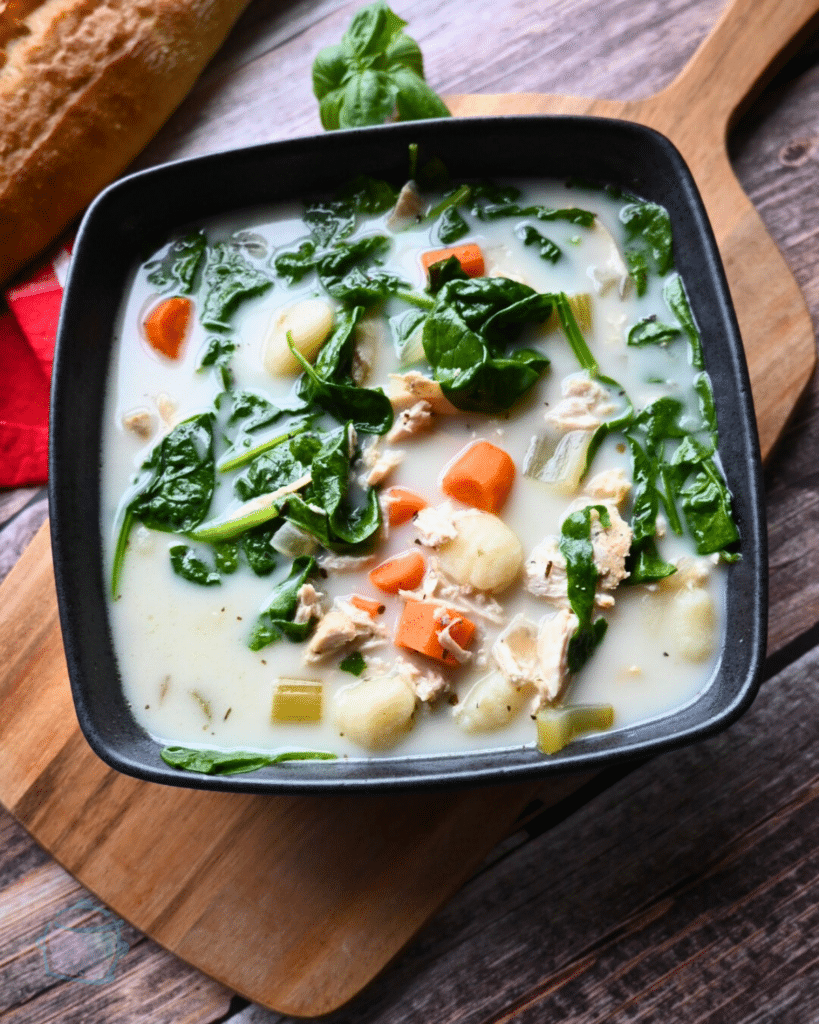 slow cooker chicken gnocchi soup in a square black bowl.