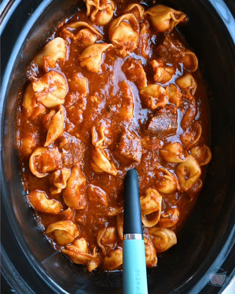 Beef and tortellini in a slow after being cooked with a spoon