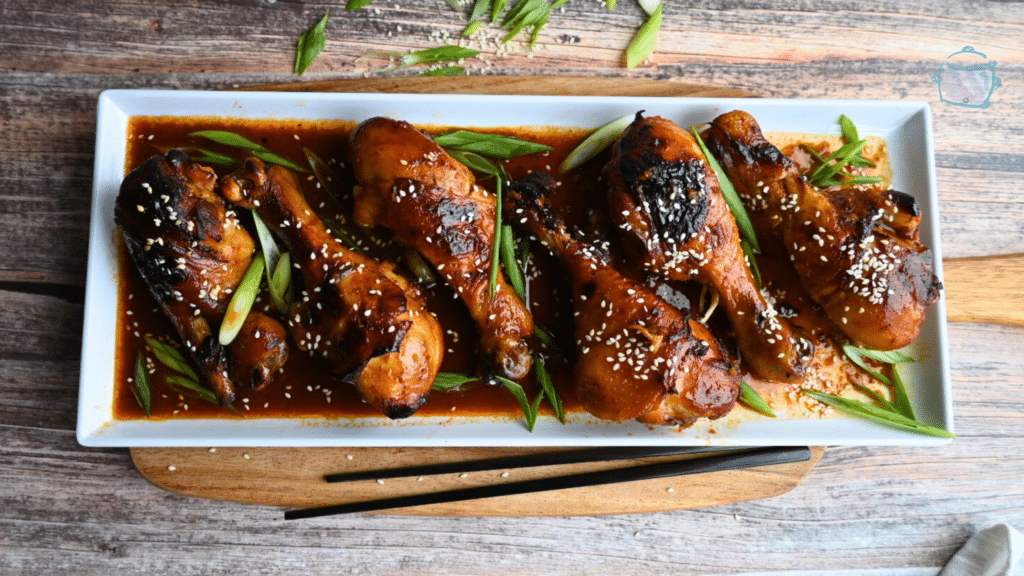 a white rectangular tray with a row of Korean spicy drumsticks