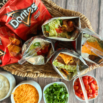 a walking taco with a plastic spoon in the middle of tray of taco toppings