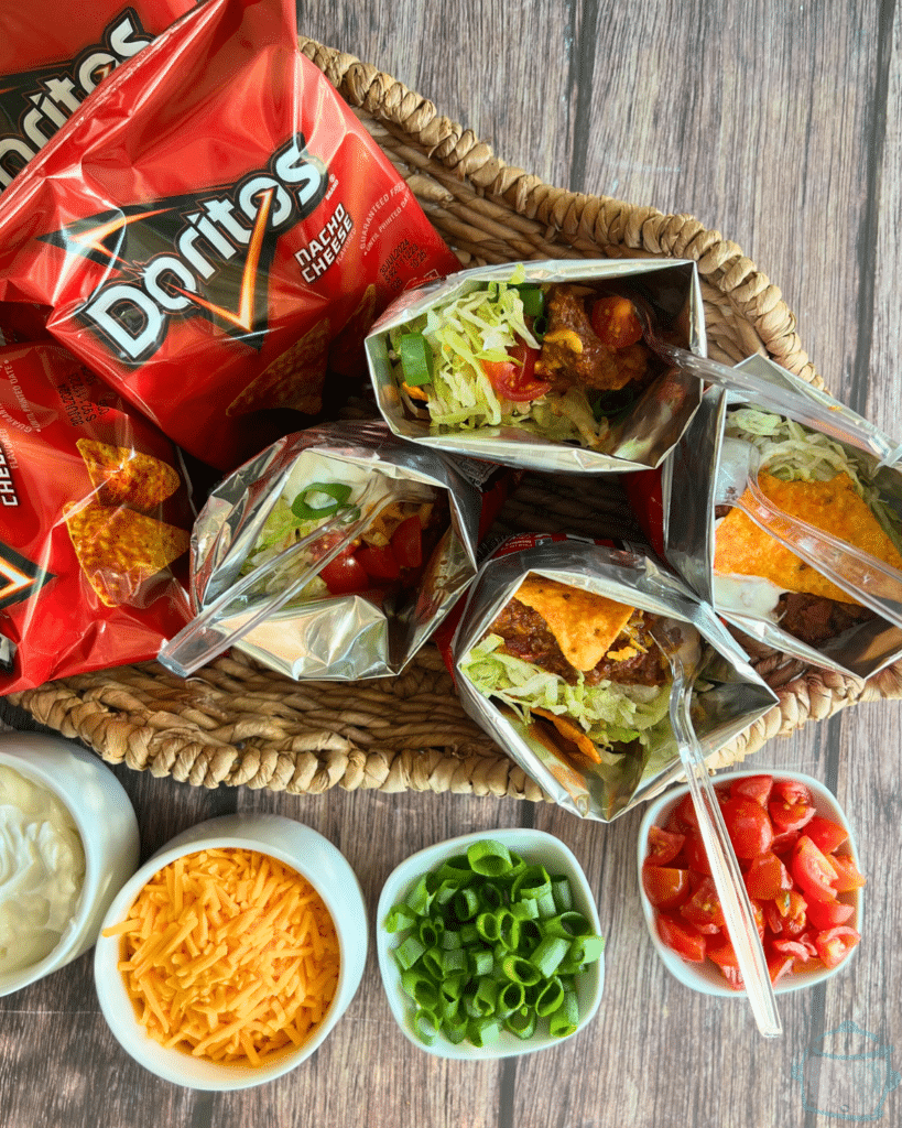 a walking taco with a plastic spoon in the middle of tray of taco toppings