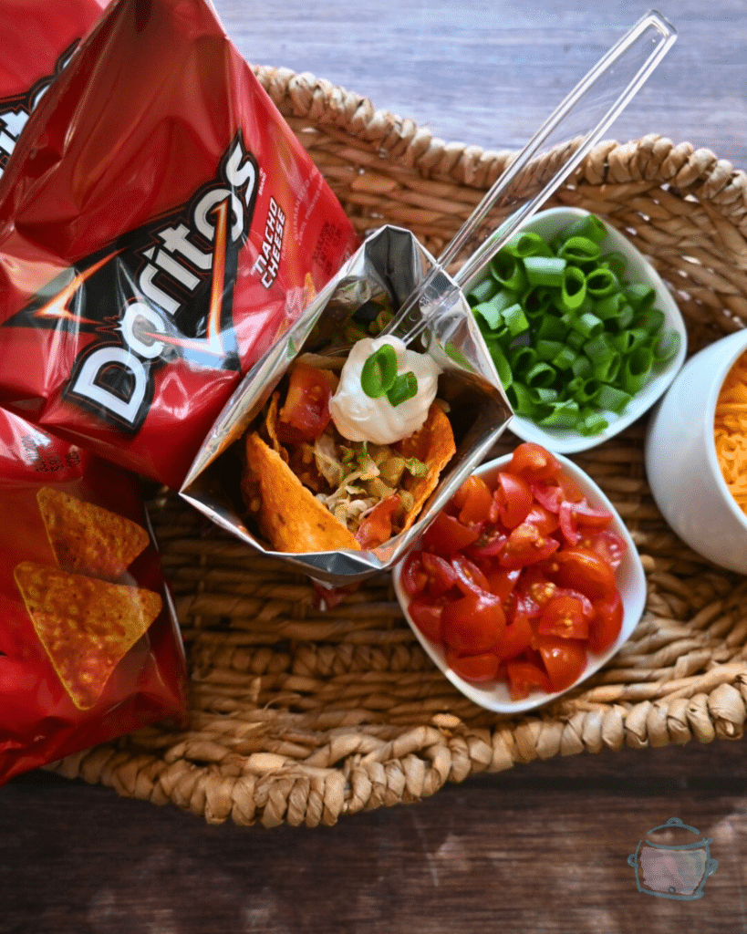 a walking taco with a plastic spoon in the middle of tray of taco toppings