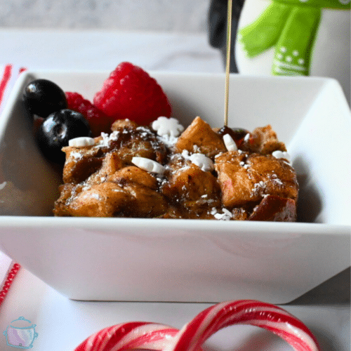 slow cooker bread pudding with sauce being poured on top