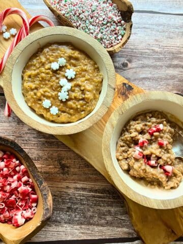 two wooden bowls of eggnog overnight oats surrounded by toppings and candy canes