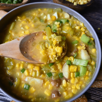 pepper and corn chowder in a round gray bowl with a wooden spoon.