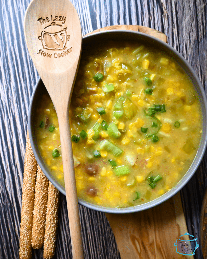 pepper and corn chowder in a round gray bowl with a wooden spoon.