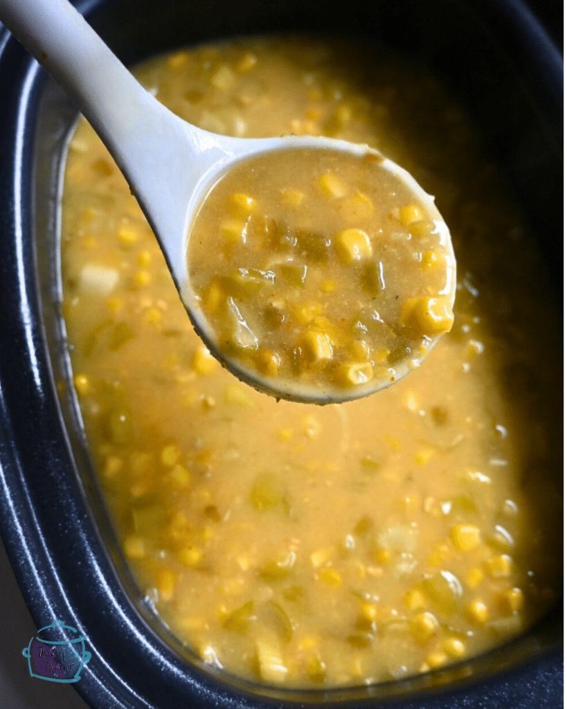 corn and pepper chowder in a ladle over a slow cooker full of the same