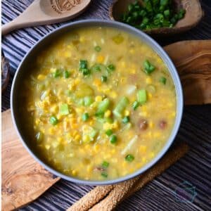 pepper and corn chowder in a round gray bowl with a wooden spoon.