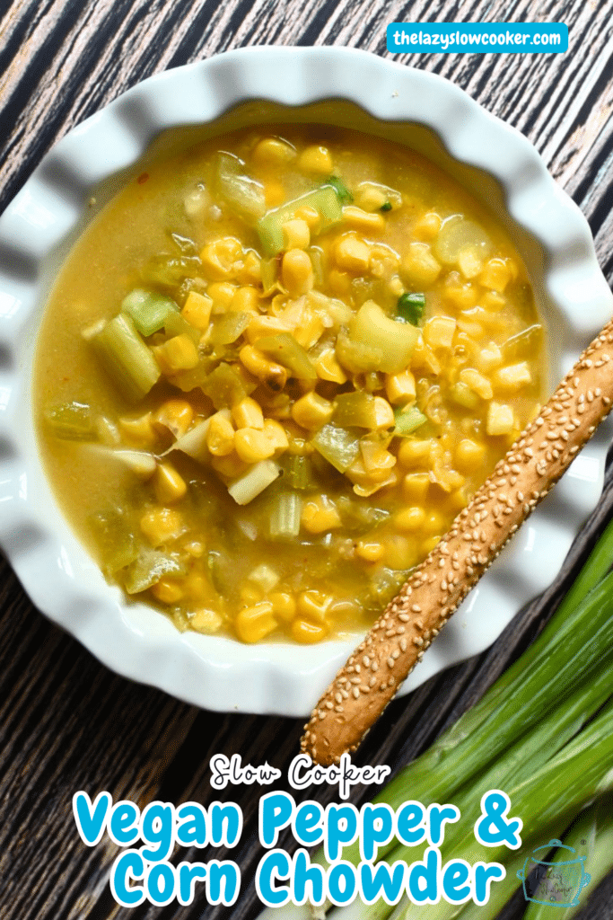 vegan corn chowder in white bowl with a bread stick on the side