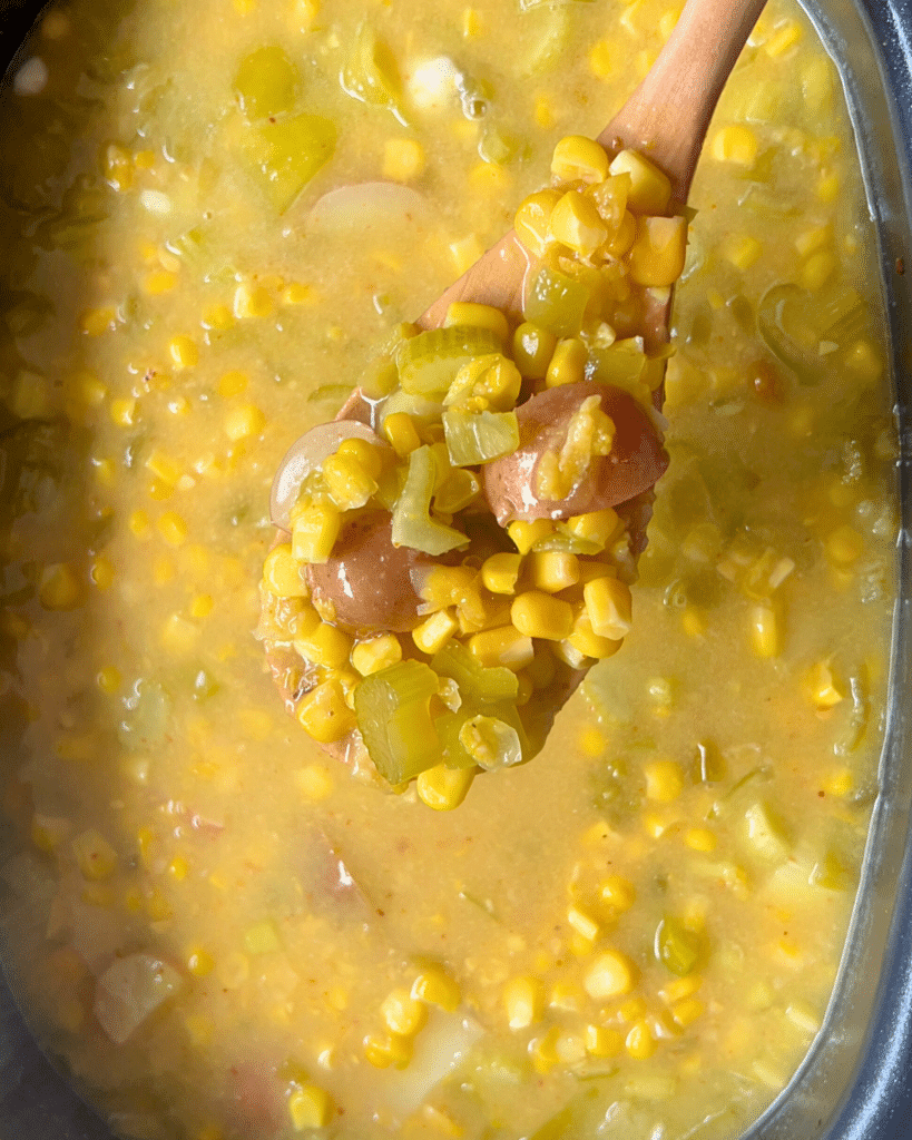 corn and pepper chowder on a wooden spoon over a slow cooker full of the same