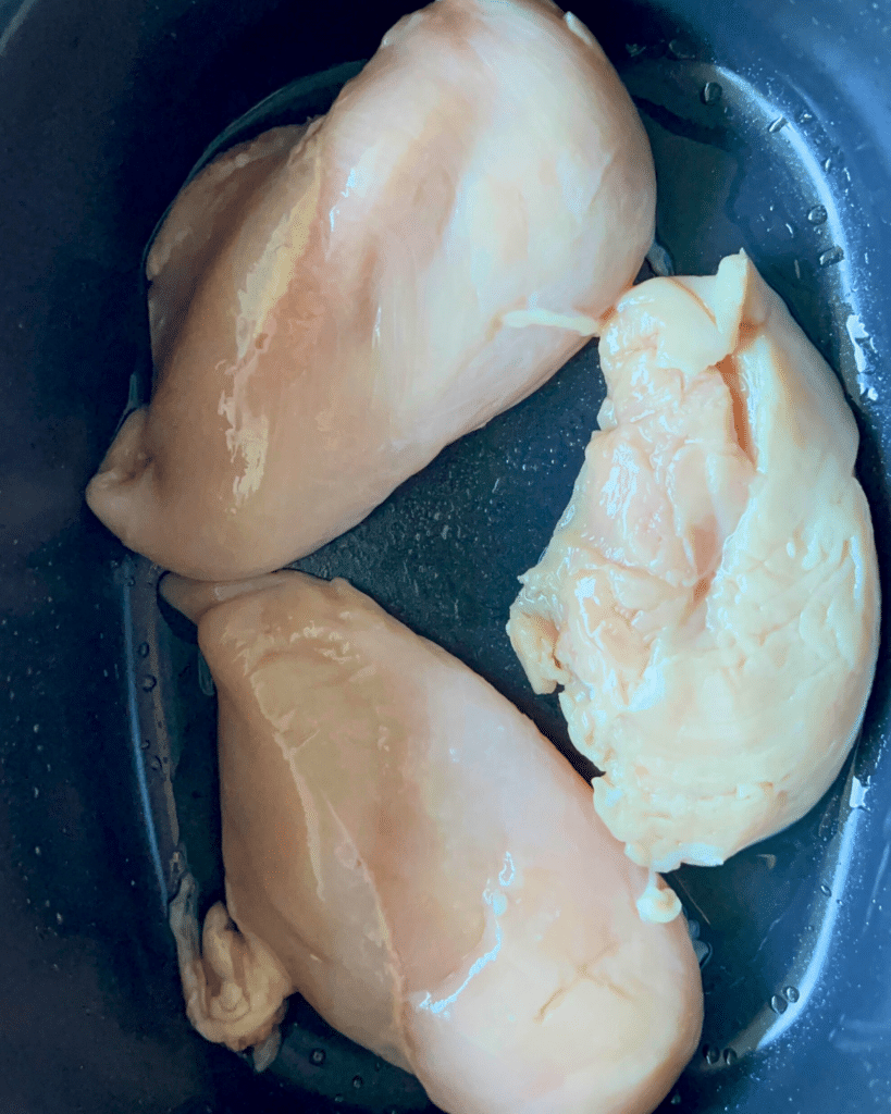 three chicken breasts in a slow cooker