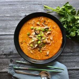 a black bowl filled with coconut Thai curry ramen with chicken