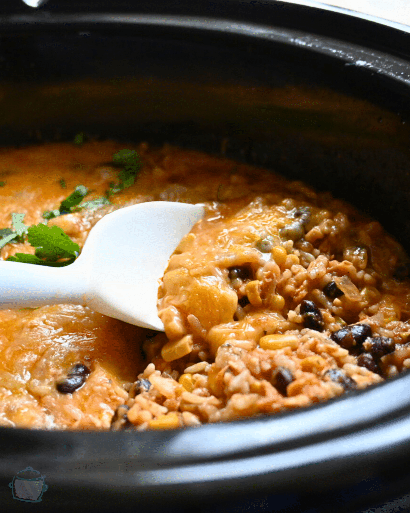 southwest chicken casserole on a spoon held over a slow cooker full of the same