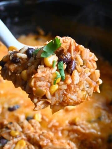 southwest chicken casserole on a spoon held over a slow cooker full of the same