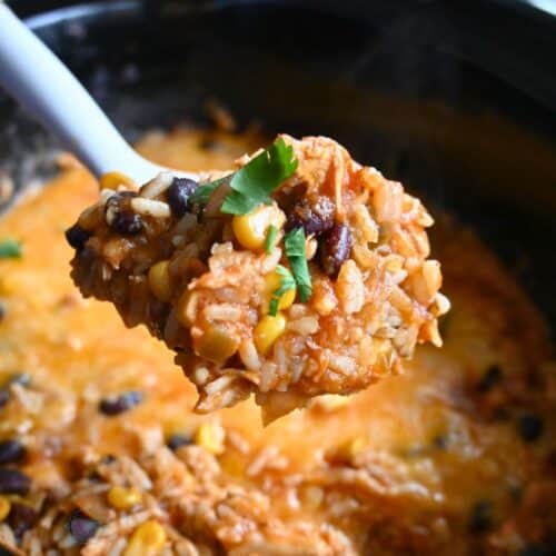 southwest chicken casserole on a spoon held over a slow cooker full of the same