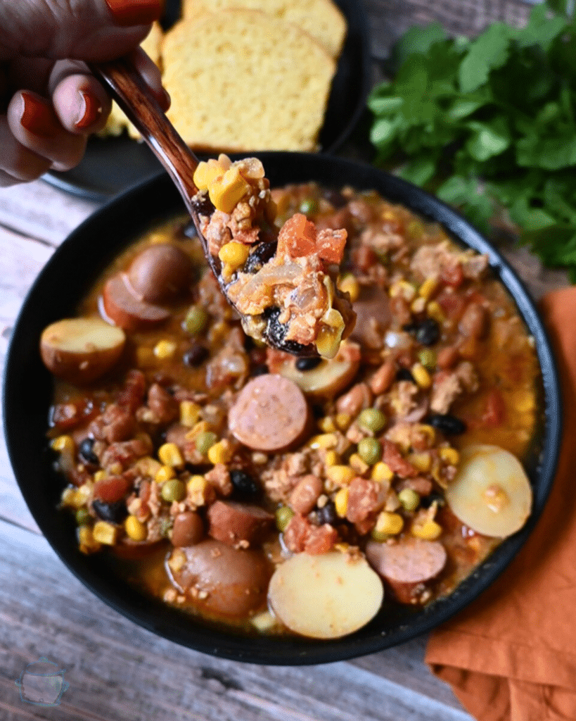 Texas cowboy stew in a black bowl with cornbread on the side