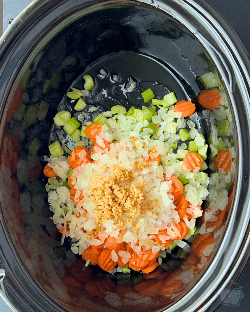 chopped veggies and spices in a greased slow cooker before cooking