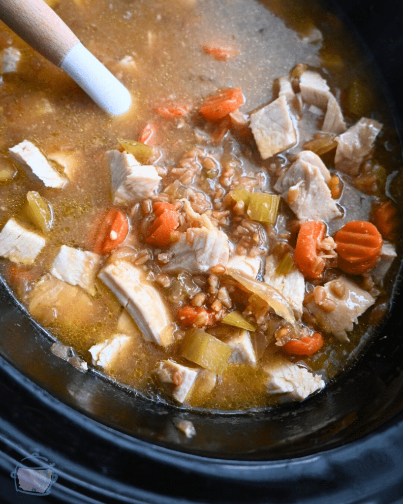 turkey miso farro soup on a ladle held over a crockpot full of the same